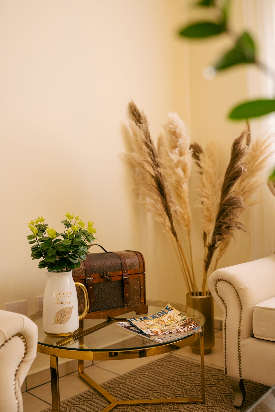 a living room with a glass table and a vase with flowers on it
